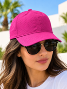 Bright pink perforated baseball cap worn by female model with sunglasses
