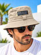 Beige UCLA label bucket hat worn by male model